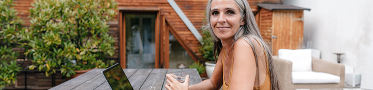 A women sitting on a picnic table with her computer 